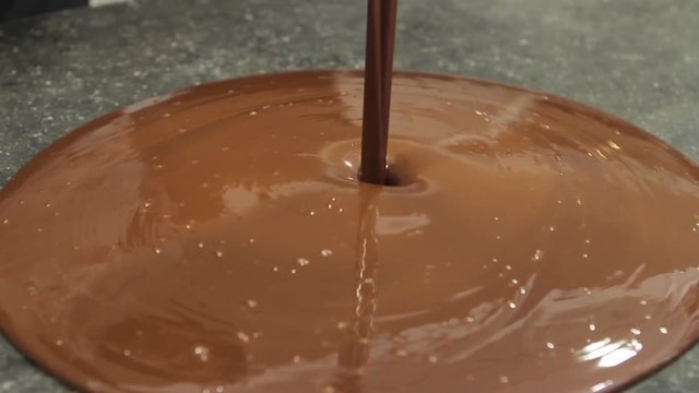 Pouring chocolade on marble table to make chocolates