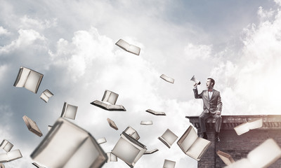 Naklejka premium Businessman on building edge announcing something in loudspeaker