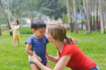 Fototapeta na wymiar Happy biracial family in the summer park - caucasian mom with her latin little son.