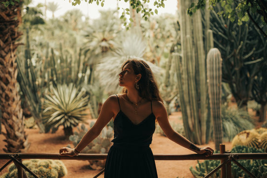 Young woman with black dress in front of cactus garden.