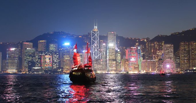 Sail junk boat travel in Victoria harbor in Hong Kong city at night