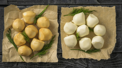 Different varieties of mozzarella cheese on paper on a wooden table.