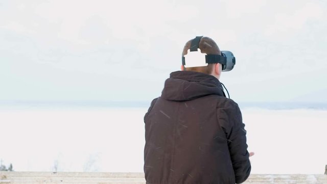 young man getting experience in using VR-headset outdoor at winter park,