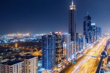 Fototapeta na wymiar Scenic nighttime skyline of big cmodern city with illuminated skyscrapers. Aerial perspective of downtown Dubai, UAE. Multicolored travel background.