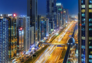 Fototapeta na wymiar Scenic nighttime skyline of big cmodern city with illuminated skyscrapers. Aerial perspective of downtown Dubai, UAE. Multicolored travel background.