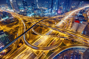 Vue aérienne du grand échangeur routier avec le trafic à Dubaï, Émirats Arabes Unis, la nuit. Paysage urbain pittoresque. Transport coloré, communications et arrière-plan de conduite.