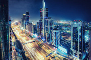 Aerial view of big highway interchange with traffic in Dubai, UAE, at night. Scenic cityscape. Colorful transportation, communications and driving background.