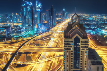 Aerial view of big highway interchange with traffic in Dubai, UAE, at night. Scenic cityscape....