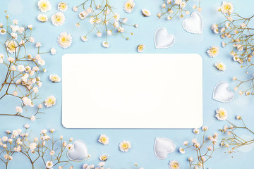 Blank paper card with gypsophila flowers on blue background. Space for text.