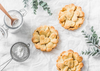 Flat lay crispy shortcrust pastry  apple tartlets on light background, top view. Valentine's day baking background