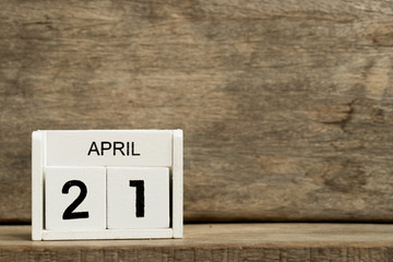 White block calendar present date 21 and month April on wood background