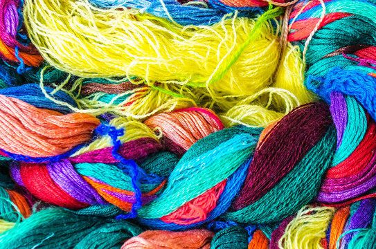 Bundles of home made colorful thread. A bundle of twisted colored threads. Multicolored yarns for knitting are interconnected. Multi-colored thread. Texture of a twisted thread.