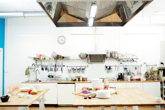 Workplace of chef with tables and kitchenware and some fresh vegetables for cooking