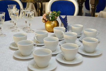 a row of white tea pairs on a white tablecloth