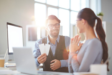 Obraz premium Young employee with two tickets offering his colleague to go to concert or performance in the evening