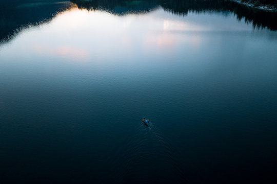 Aerial view of Father and son in kayak on lake Eibsee in Germany during sunset with forest and mountains