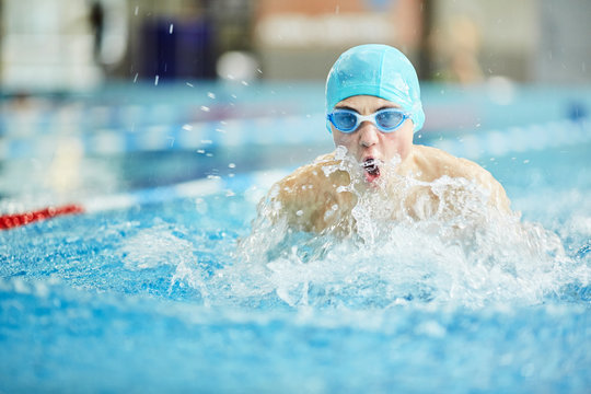 Young guy in swimwear swimming in water during sports competition