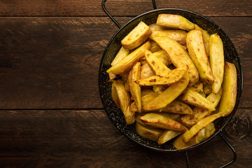 Crunchy roasted potatoes in skillet on dark rustic texture