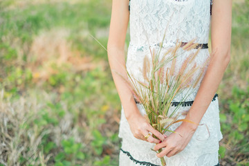 Young woman holding grass flowers.