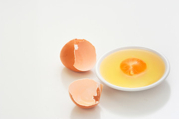 Broken eggshells with egg yolks in white bowl