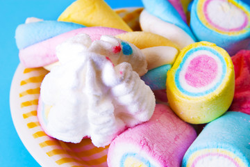Fototapeta na wymiar sweet. plate full of colorful marshmallows on blue background
