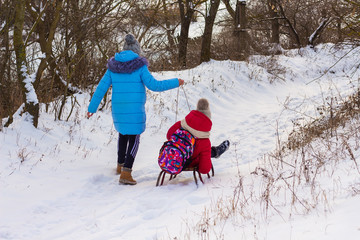 Fototapeta na wymiar two girls ride a sled, a fine winter day
