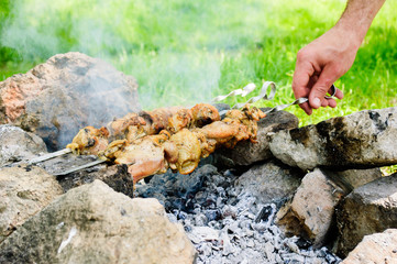 Chicken meat on skewers outside with smoke and cook hand - outdoors autumn winter party