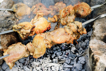 Chicken meat on skewers on the stones over charcoal.