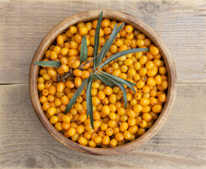 Sea buckthorn in a wooden bowl. Fresh harvest berries from the garden