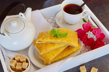 Cheesy pancakes with tea on a wooden tray.
