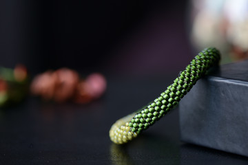Handmade beaded bracelet two shades of green on a dark background close up