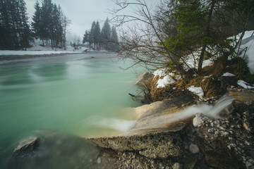  The river isar with turquoise water in winter on a foggy winter day at the sylvensteinspeicher