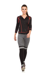Fototapeta premium Smiling Young Woman In Sports Clothes Is Walking Towards Camera. Front View. Isolated.