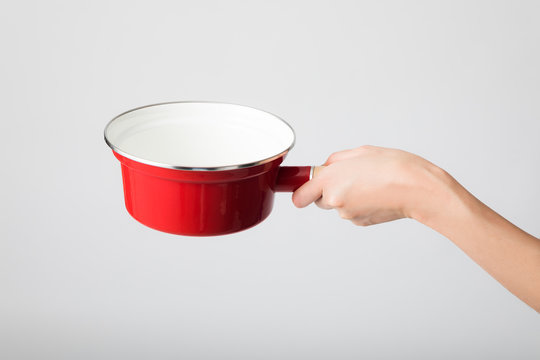 Hand holding a  single-handled pot.
