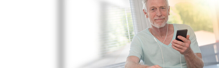 Portrait of mature man listening music with earphones, light effect