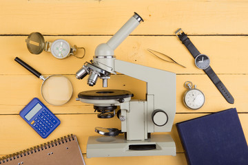 Education concept - notepad, microscope on the yellow wooden desk