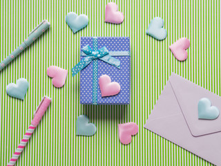 Blue gift box, hearts and envelope on pastel green. Flat lay Valentine's woman mother day concept