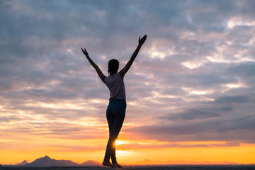 Fototapeta na wymiar Silhouette of free woman enjoying freedom feeling happy at sunset. Serene relaxing woman in pure happiness