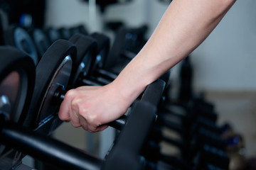Obraz na płótnie Canvas human's hand, taking dumbbell in gym