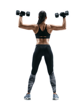 Young woman bodybuilder doing exercise with dumbbells. Photo of sporty woman in training pumping up muscles of the back and hands on white background. Rear view. Full length