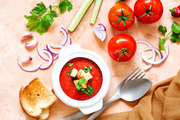 Fresh, healthy tomato soup with basil, pepper, garlic, tomatoes and bread on wooden background. Spanish gazpacho soup. Top view. Copy space