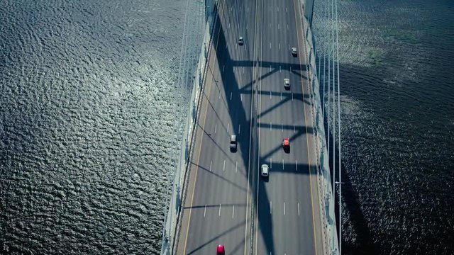 Car traffic on hanging sea bridge over bay in city view from above