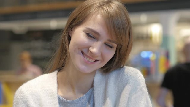 Portrait of Smiling Young Woman Looking at Camera in Cafe