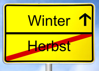 Gelbes Ortsschild zeigt Ende des Herbstes und Beginn des Winters