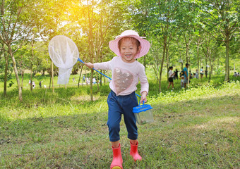 Adorable little asian girl wear straw hat in a field with insect net in summer.