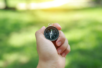 Compass in hand against nature background.