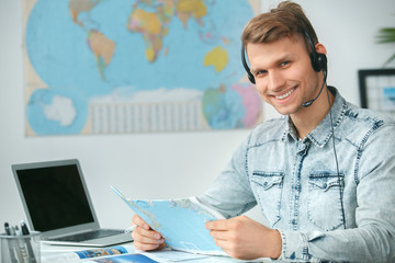 Young male travel agent consultant in tour agency holding map