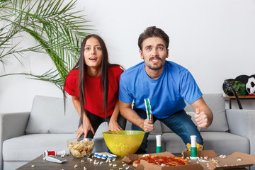 Young couple sport fans watching match excited