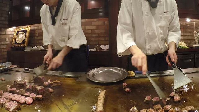 Chef cooking and cutting raw fresh Kobe beef steak teppanyaki on hot plate at Kobe, Japan