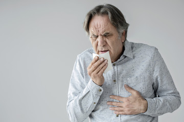 Old man coughing to tissue